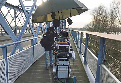 Sur la passerelle, un peu à l'écart, le preneur de son récupère en VHF le son des micros cravates disposés sur les acteurs. Comme une pluie va être déclenchée, un gros parapluie protège le matériel